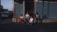 a group of young men sitting on the side of a building