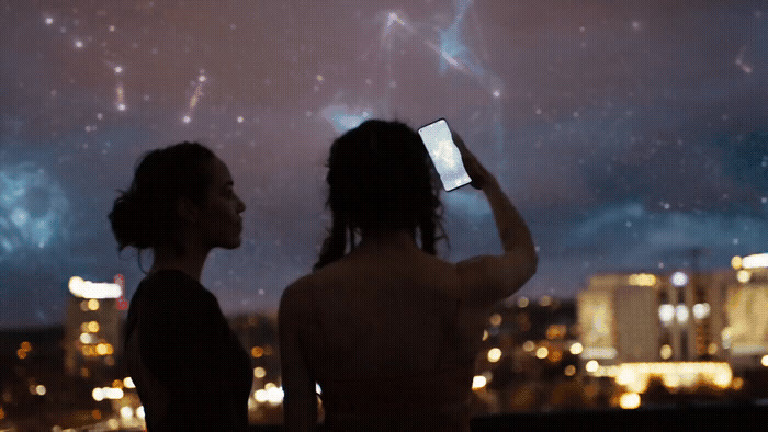 two women taking a picture of a city at night