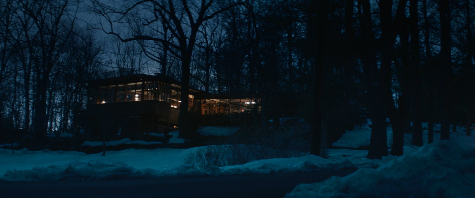 a cabin in the woods at night with snow on the ground