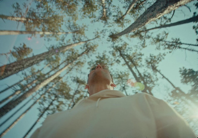 a man looking up into the sky in a forest