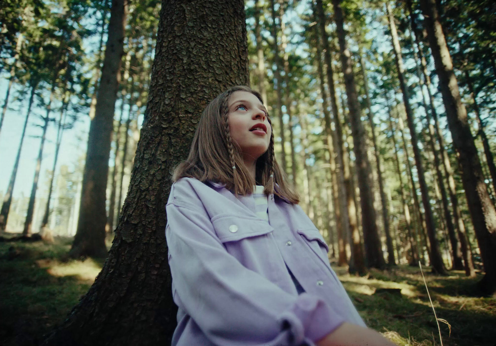 a woman standing in front of a tree in a forest