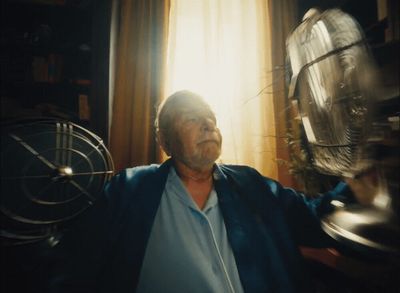 a man standing in front of a window next to a fan