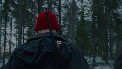 a man in a red hat is walking through the woods