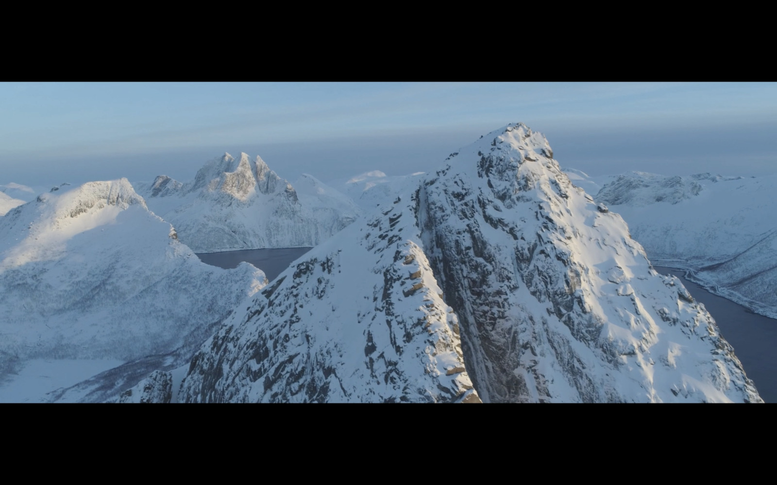 a mountain range covered in snow with mountains in the background