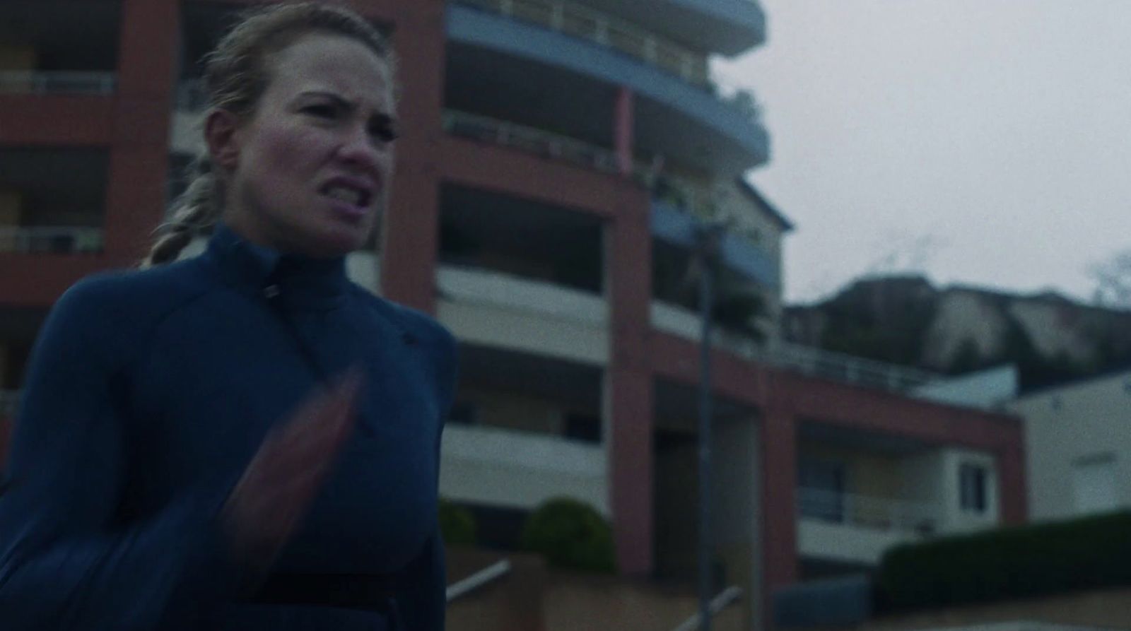 a woman in a wet suit running in front of a building