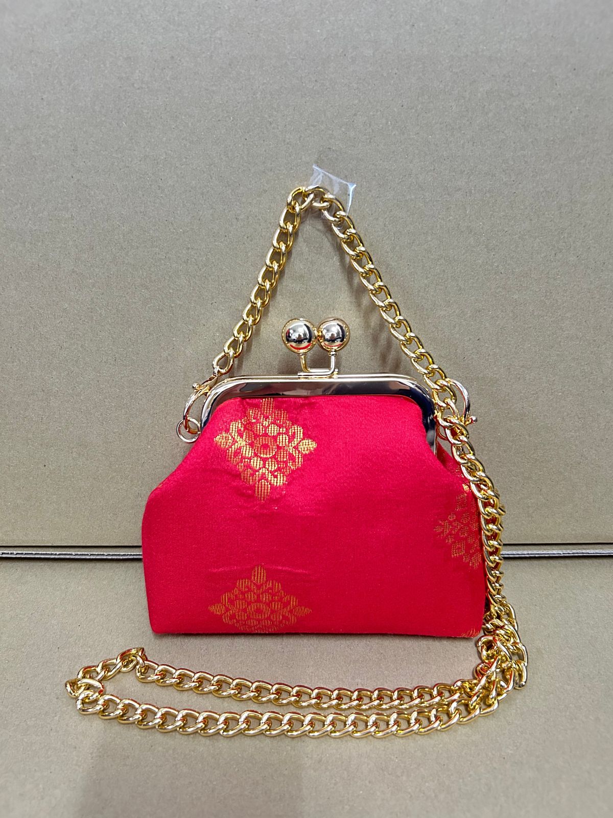 a pink purse with a gold chain hanging from it