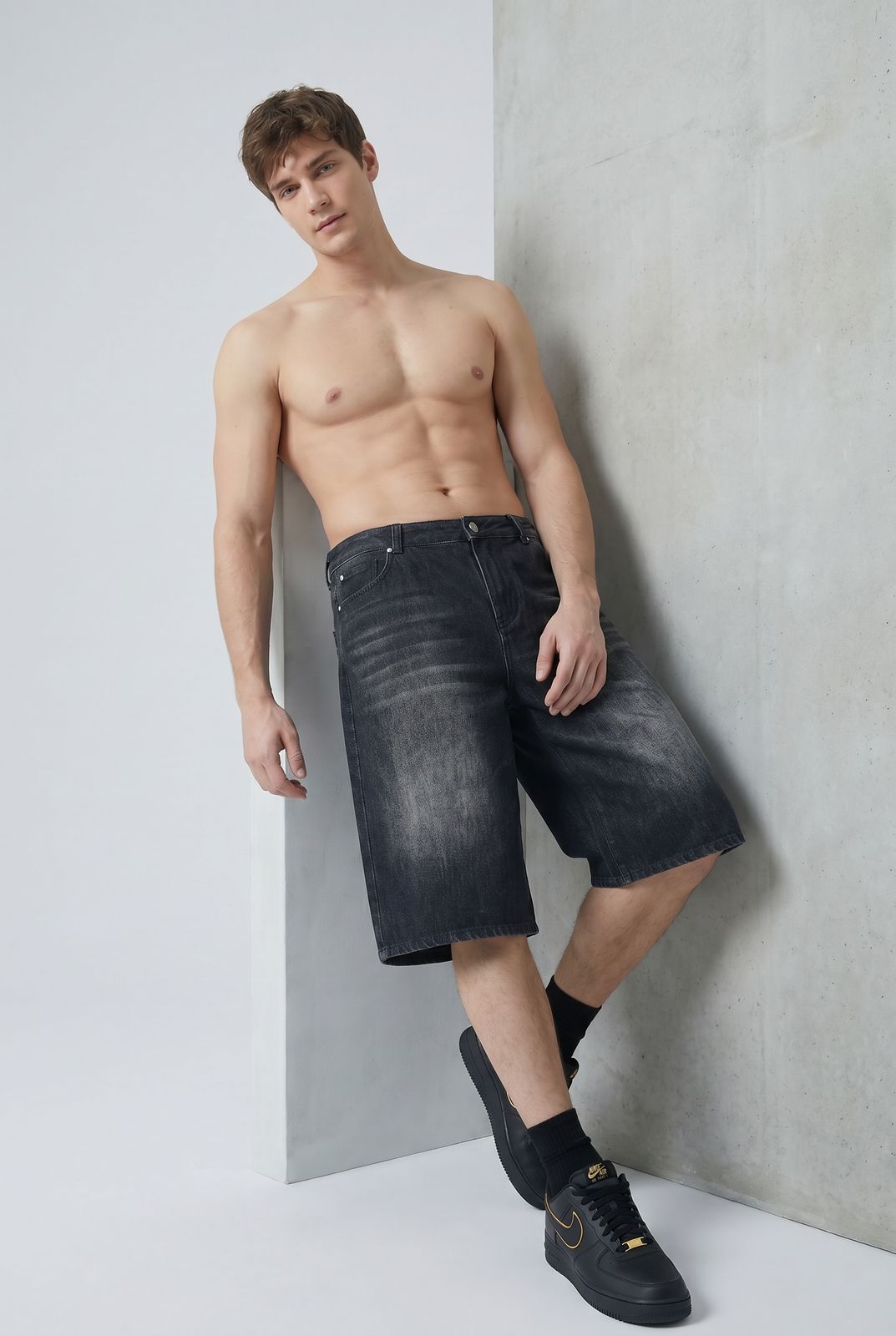 a shirtless man leaning against a wall