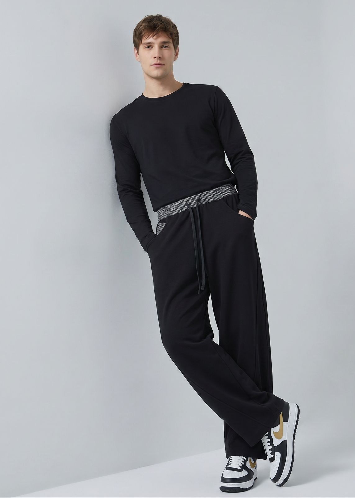 a man in black is leaning against a wall