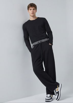 a man in black is leaning against a wall