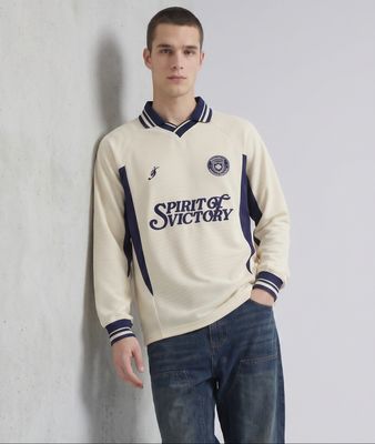 a young man standing against a wall wearing a sweater