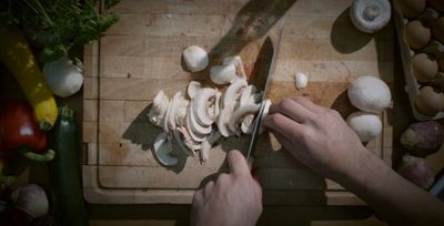 a person chopping mushrooms on a cutting board