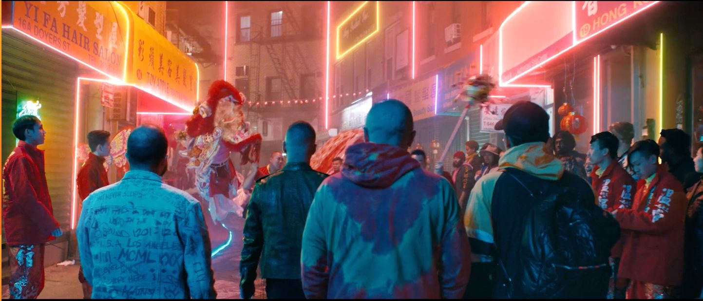 a group of people walking down a street next to tall buildings