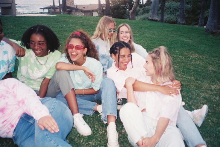 a group of young women sitting on the grass