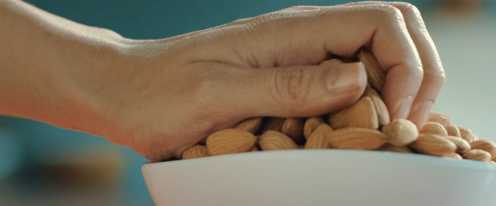 a person holding a bowl of nuts in their hand