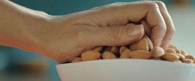 a person holding a bowl of nuts in their hand