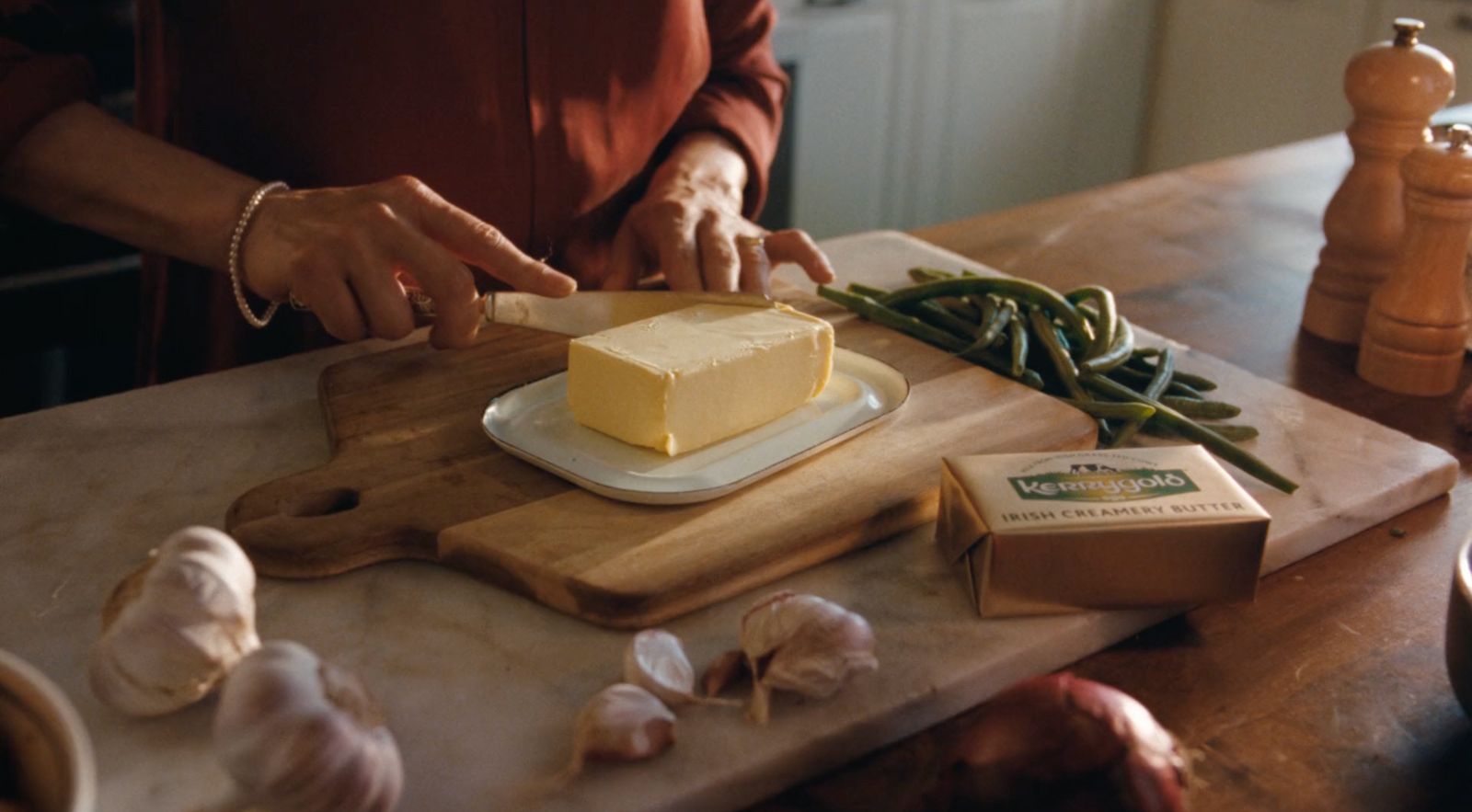 a person cutting up a piece of cheese on a cutting board