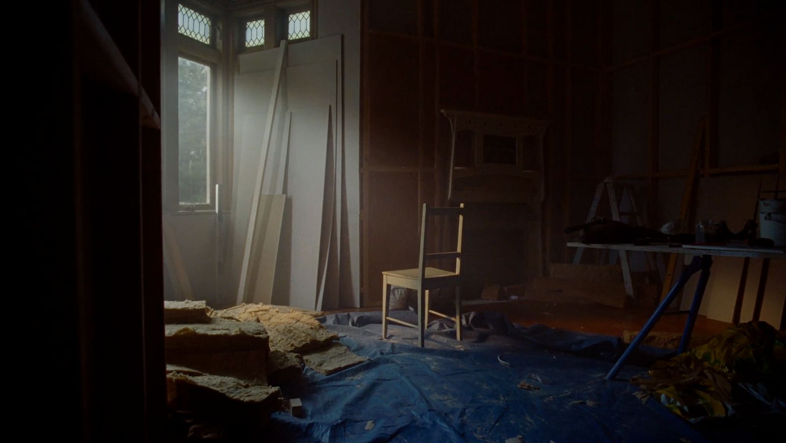 a dark room with a chair and a window