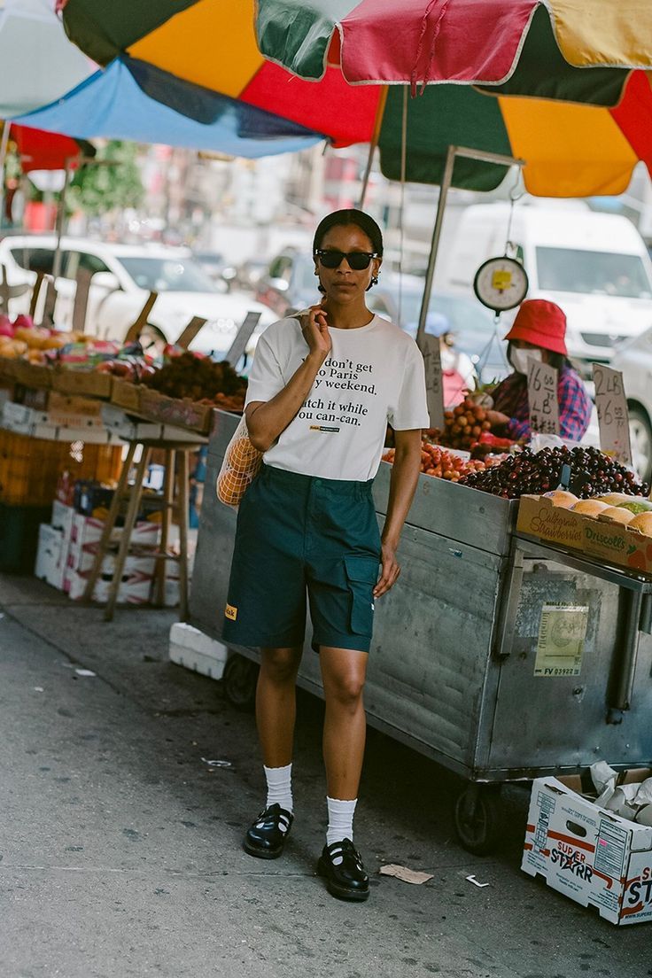 a man standing under an umbrella next to a fruit stand