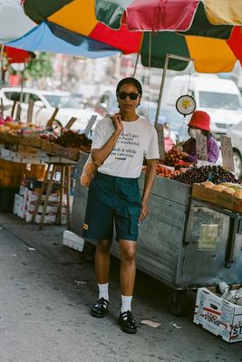 a man standing under an umbrella next to a fruit stand