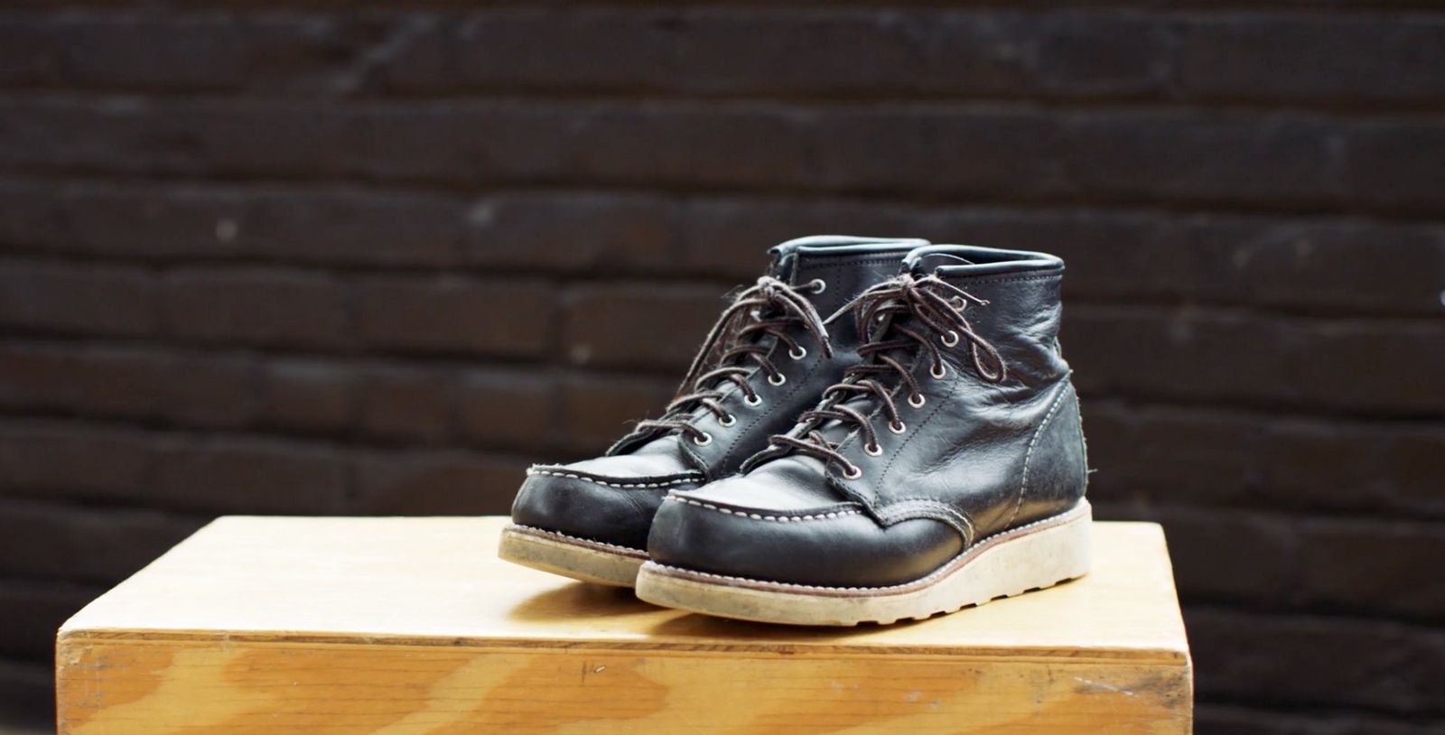 a pair of black shoes sitting on top of a wooden block