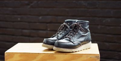 a pair of black shoes sitting on top of a wooden block