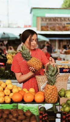 a woman holding a pineapple in a market