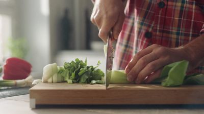 a person cutting up vegetables on a cutting board