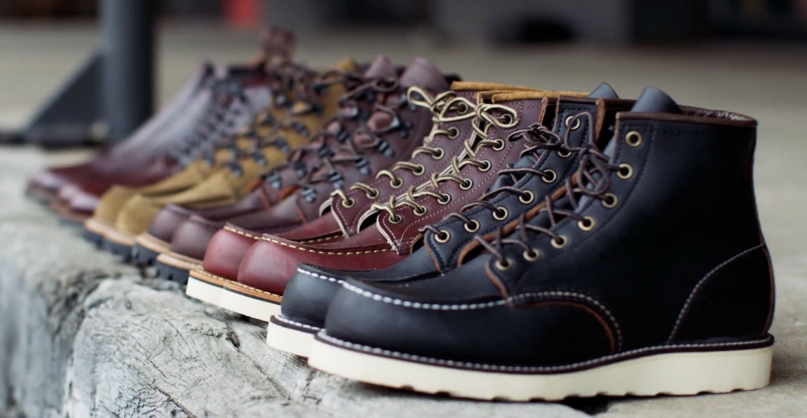 a row of different colored boots sitting on top of a stone wall