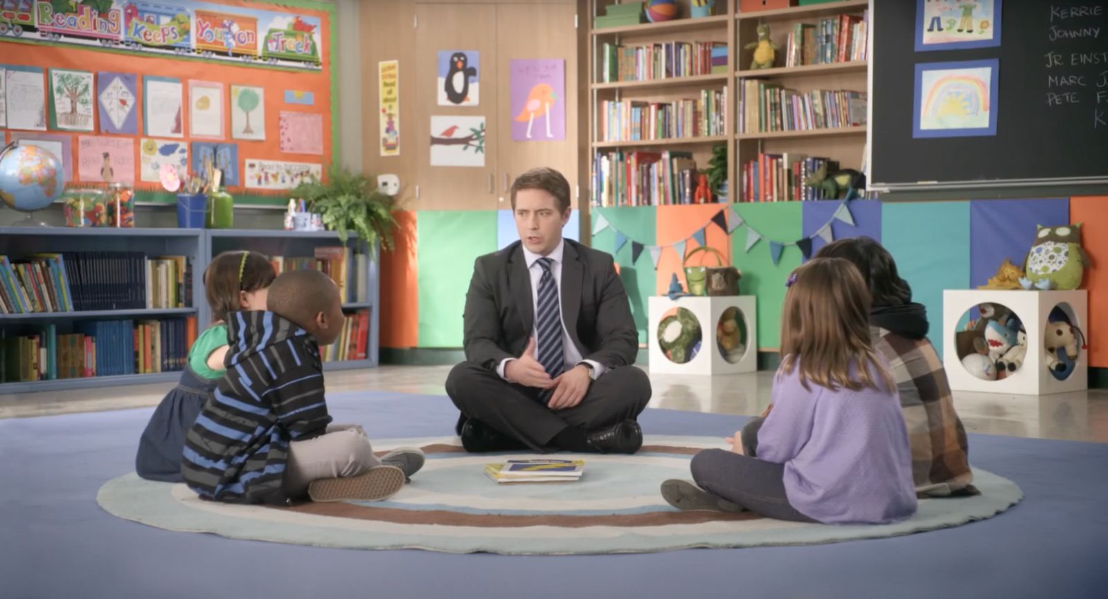 a man sitting on the floor in front of a group of children