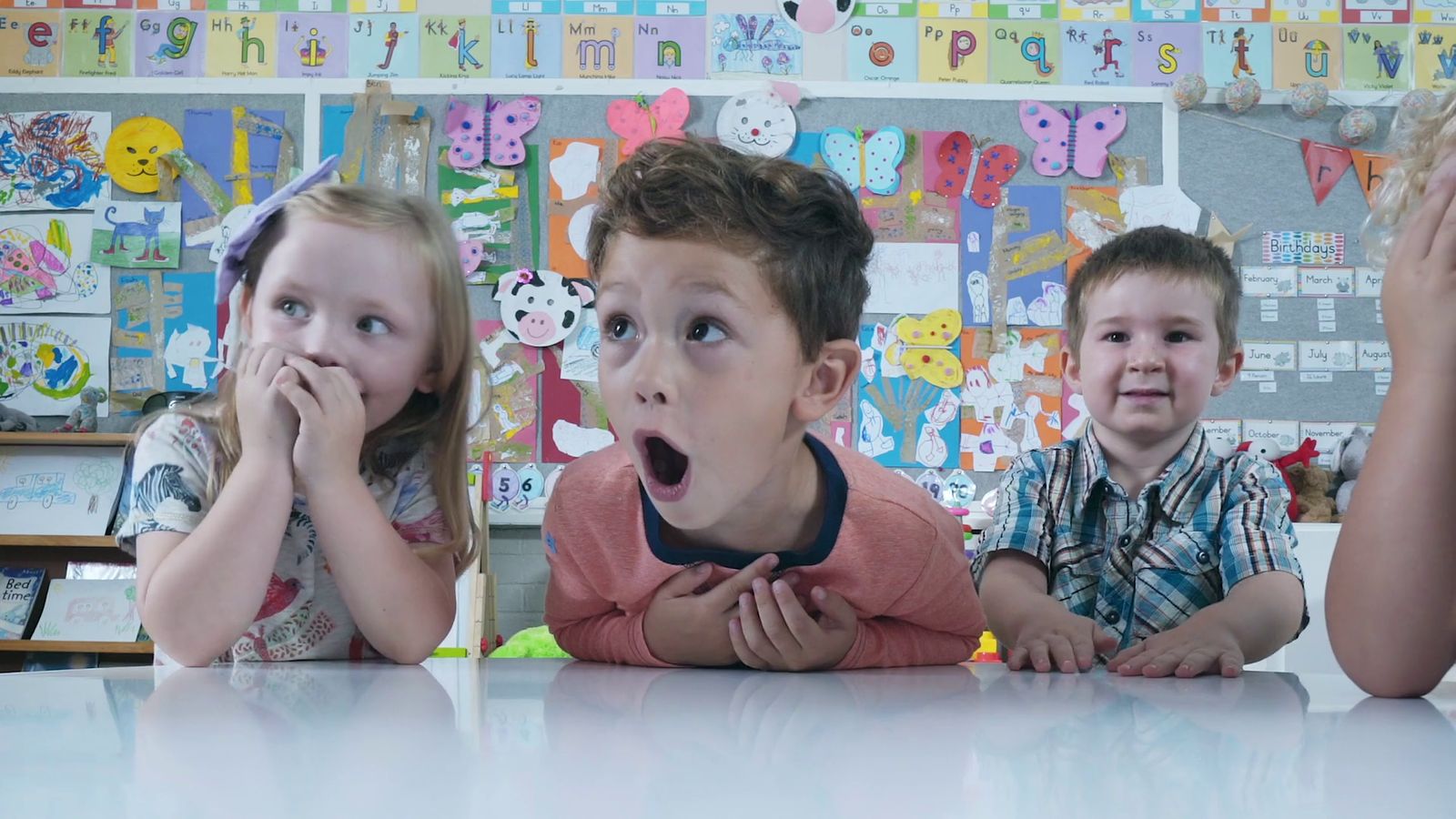 a group of children sitting at a table with their mouths open