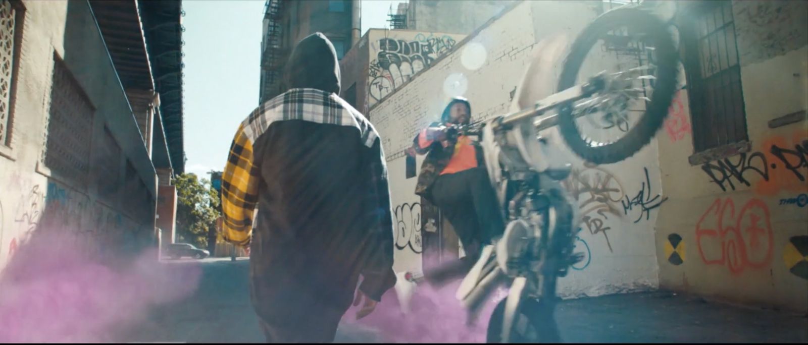 a man riding a bike down a street next to graffiti