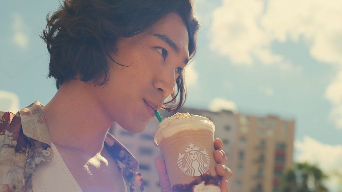 a man drinking a starbucks drink with a straw in his mouth