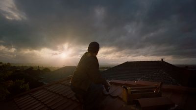a man standing on top of a roof under a cloudy sky