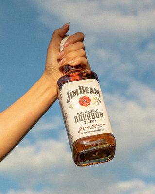 a person holding a bottle of bourbon in their hand