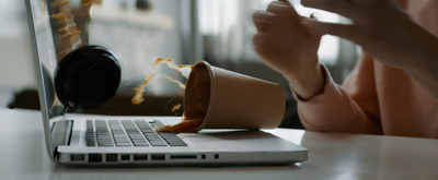 a woman drinking coffee while using a laptop computer