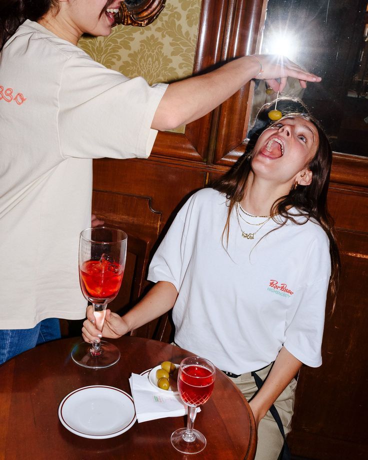 a woman sitting at a table with a glass of wine