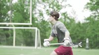 a young man holding a lacrosse racquet on top of a field