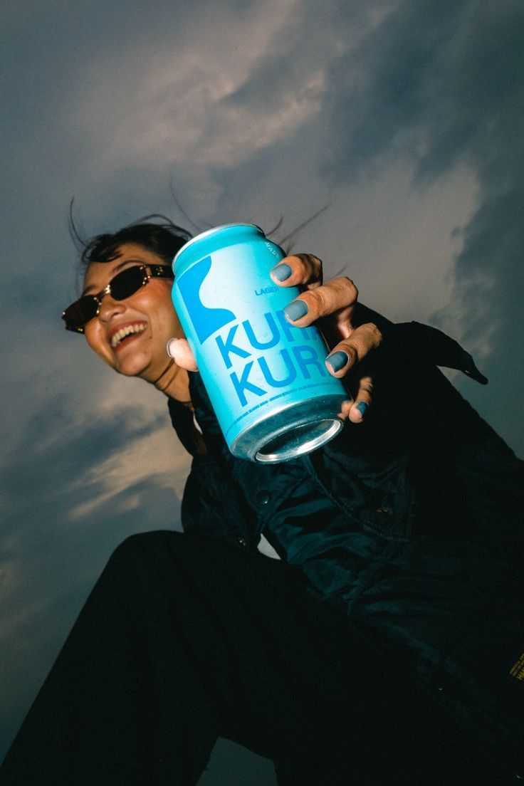 a woman is holding a can of klu kluk on a cloudy day