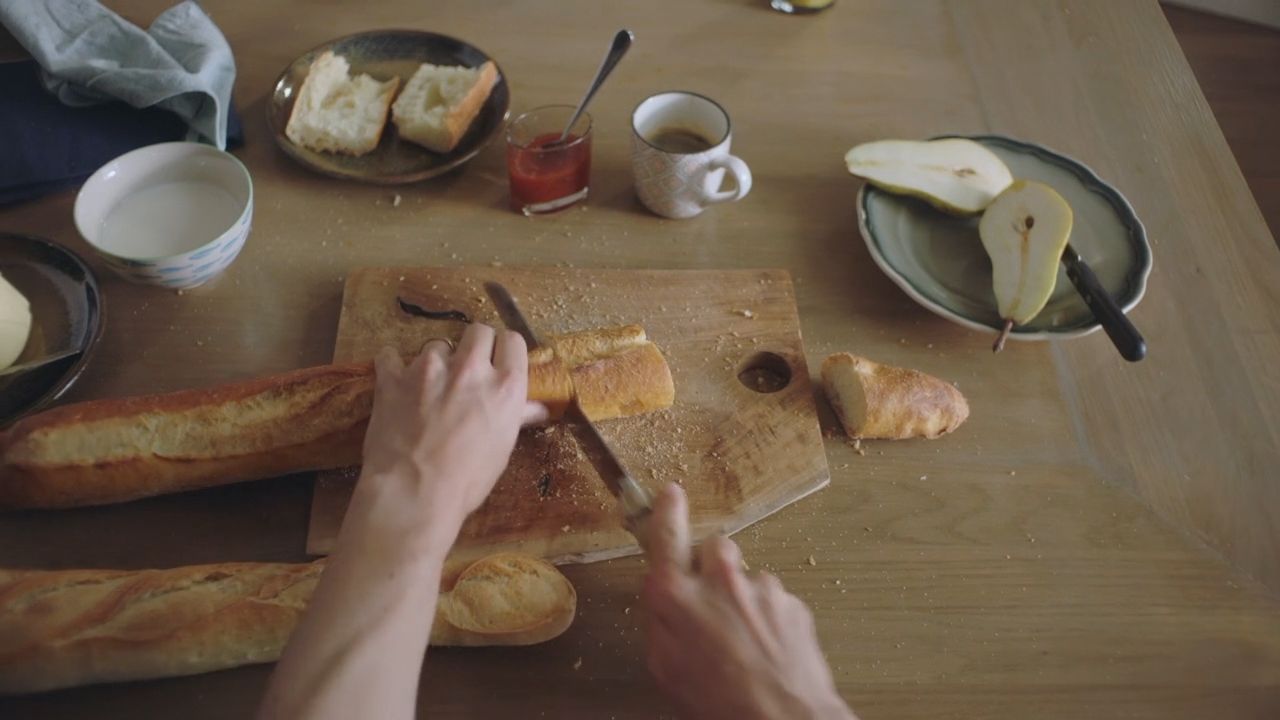 a person cutting bread on a cutting board