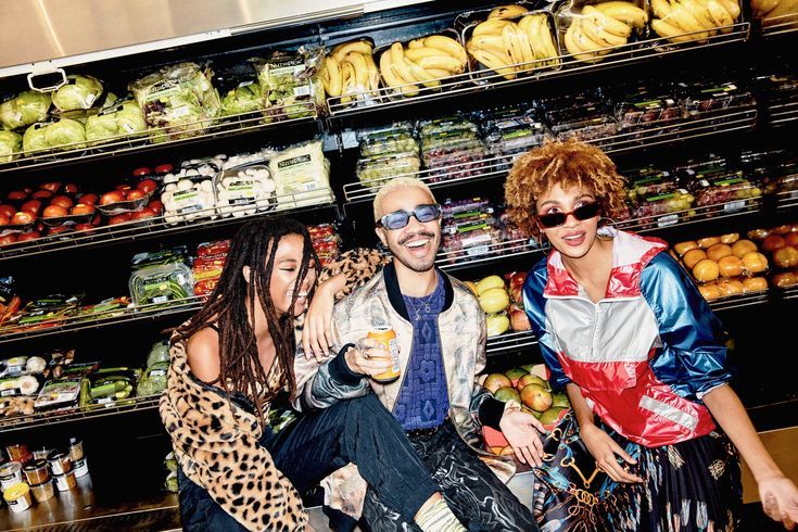 a group of people standing in front of a display of fruits and vegetables