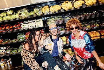 a group of people standing in front of a display of fruits and vegetables