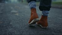 a person walking down a street wearing brown boots