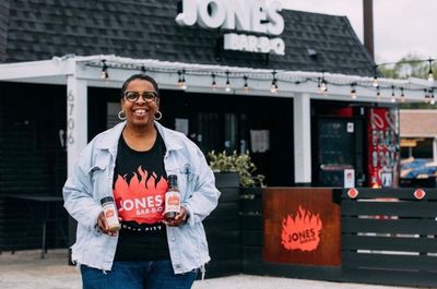 a woman standing in front of a building holding a beer