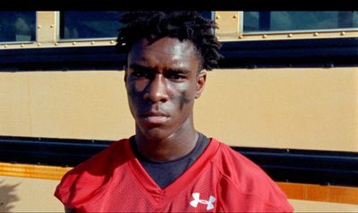 a man in a red jersey standing in front of a school bus