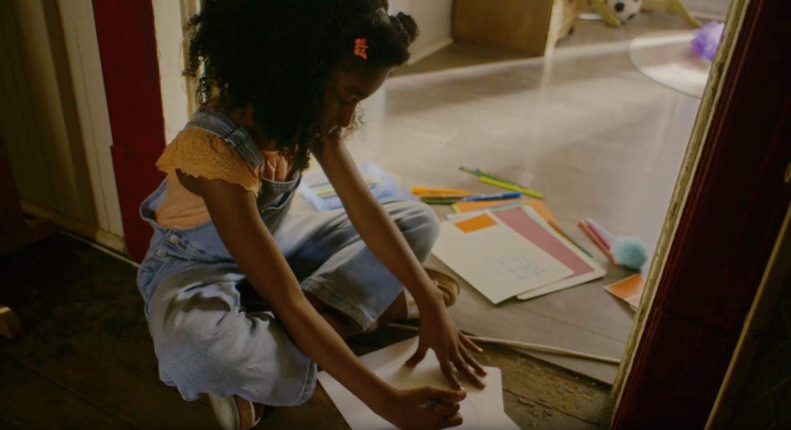 a little girl sitting on the floor with a piece of paper