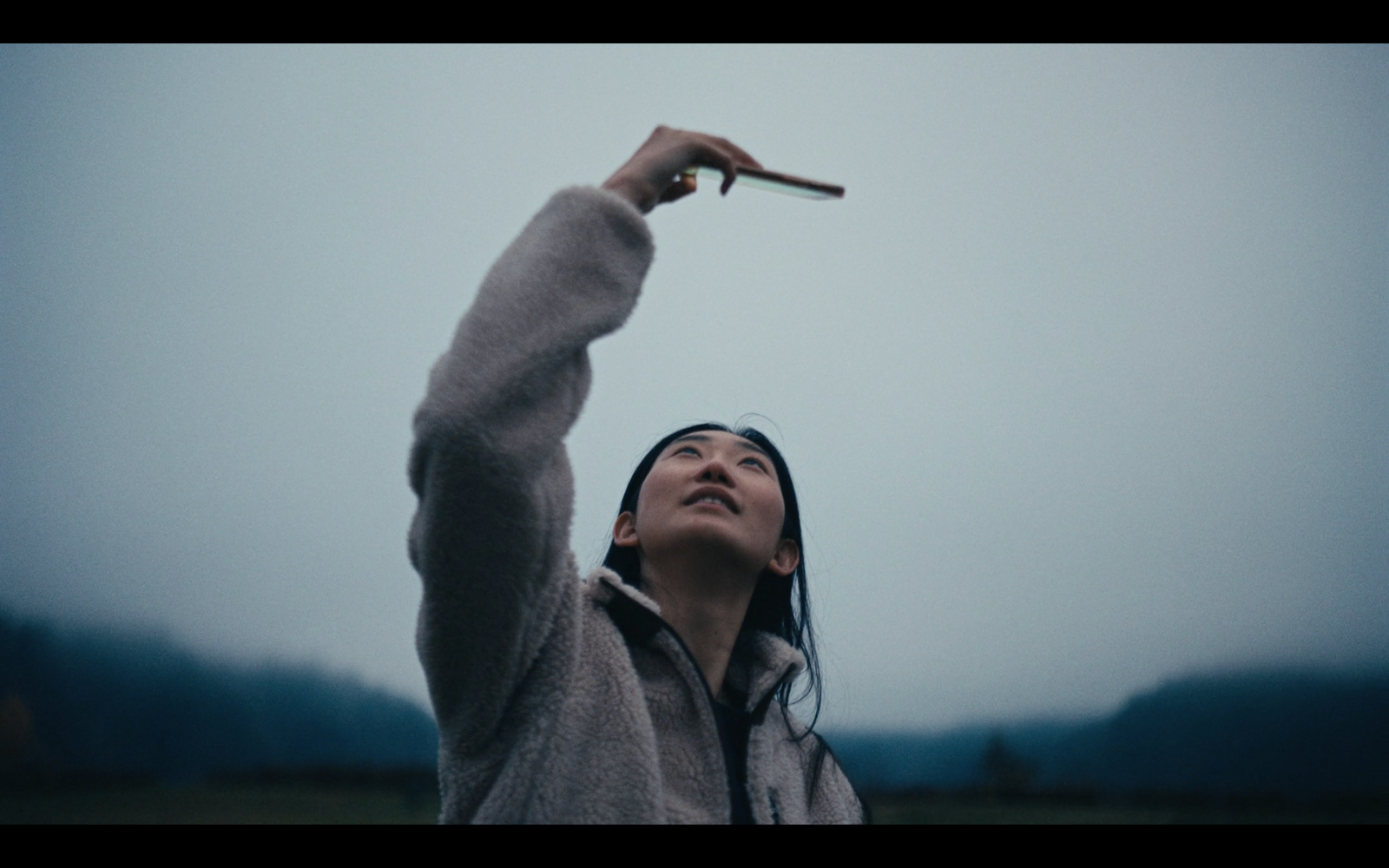 a woman reaching up to a kite in the sky