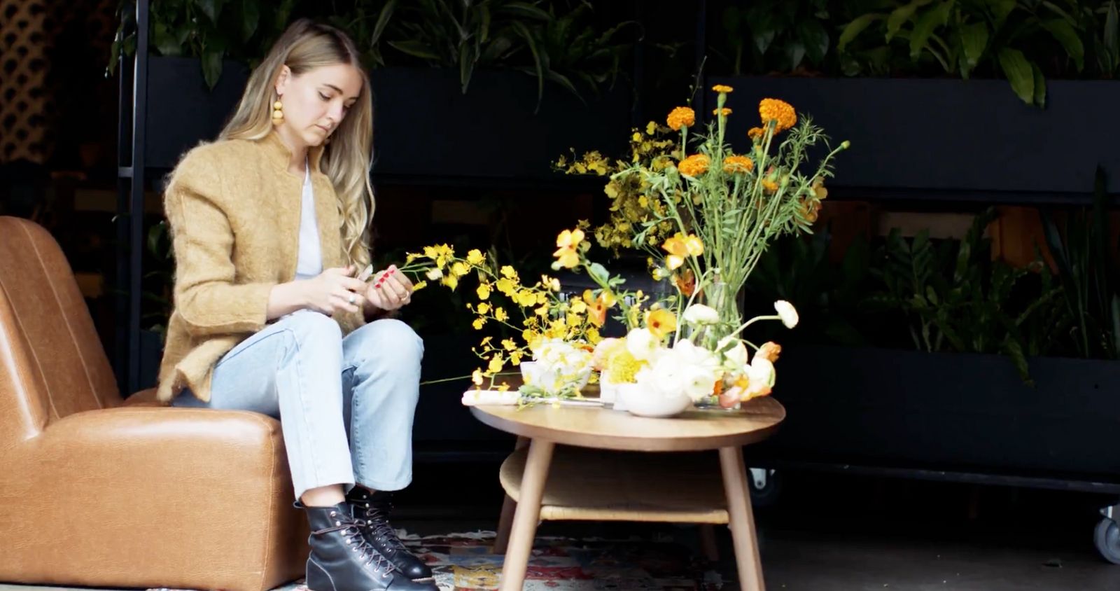 a woman sitting on a chair next to a table with flowers