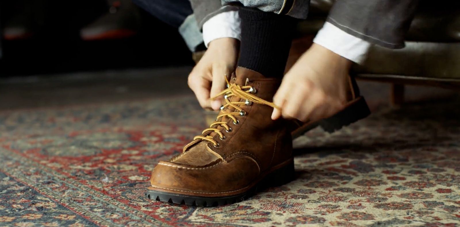 a person tying a shoelace on a rug