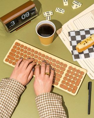 a person typing on a keyboard next to a cup of coffee