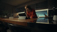 a woman sitting at a table using a laptop computer